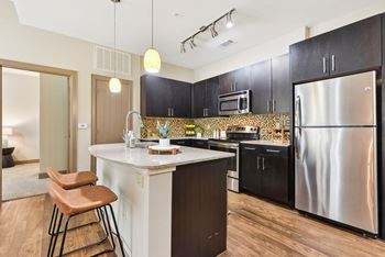 A kitchen with stainless steel appliances and a marble counter top